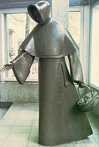 A stylised metal statue of a hooded woman holding a basket.