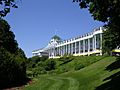 Large hotel atop a short rise with a wide verandah, set among manicured lawns and greenery.