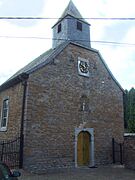 Religious building in stone in Romanesque style with a bell tower and clock.