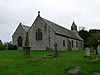 A simple church with a double nave, that on the right being the higher; at the far end is a bellcote containing two bells; in the foreground are gravestones in various shapes, including a cross