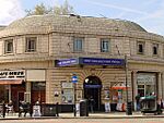 A beige-bricked building with a blue sign reading "GREAT PORTLAND STREET STATION" in white letters all under a blue sky with white clouds