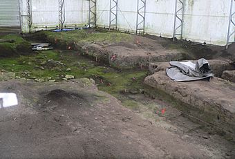 Trenches in bare earth; inside fabric-walled building