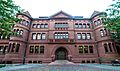 A large brick academic building. It has some ornate decorations, and two rounded sections separate the central portion from wings on either side.