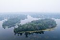 Two small, oblong islands sit in the side of Lake of the Isles, viewed from the air on a smokey day.