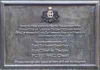 Oblong, brown plaque bearing the words "Near to this spot on the 16 December 1910 three City of London Police Officers were fatally wounded whilst preventing a robbery at 199 Houndsditch. In commemoration of Sgt Robert Bentley, Sgt Charles Tucker, PC Walter C Choat whose courage and sense of duty will not be forgotten."