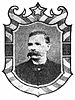 Framed portrait of a white man with an extremely bushy mustache, wearing a dark suit coat and bow tie.