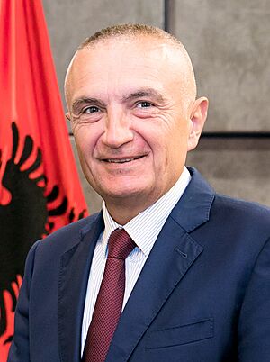 Head shot of Meta smiling with an Albanian flag in the background