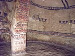 Interior of a cave with wall paintings of geometrical figures in red, black and white.