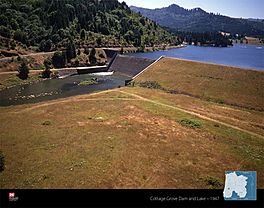 View upstream of a grass-covered dam impounding a lake