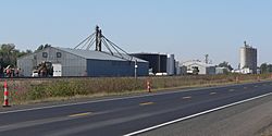 Metal building with "Buda Corn & Storage" on side; large metal tanks; grain elevators