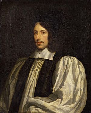 A middle-aged white man seated and dressed in clerical robes.