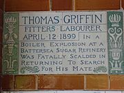 A tablet formed of two large tiles, bordered by green flowers in the style of the Arts and Crafts movement