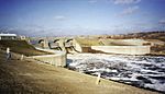  A small river rushes away from the base of a dam.