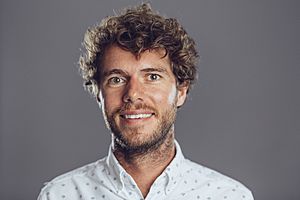 A white man in his 30s, with brown hair, smiling awkwardly at the camera.