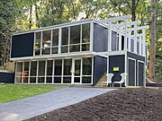 A two-level, slightly larger No. 5 house, painted gray with white window trim that was built into the slope on a cinder-block base.