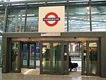 A dark grey doorway with a person walking through it and a white sign above with a red circle on it and letters reading "UNDERGROUND"