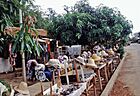 A market stall selling hats, surrounded by trees.