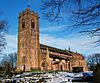 A red sandstone church with a tall battlemented west tower