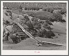 Irrigation-water-crossing-ditch-in-hollowed-out-log-trampas-new-mexico-aab3