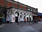 A white building with a rectangular, white sign reading "Vauxhall" in black letters and four bicycles in front all under a grey sky