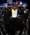 A colour photograph of three members of Yellow Magic Orchestra at the front of a stage