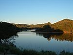 A lake with a forest in the background, which is reflecting upon the water.