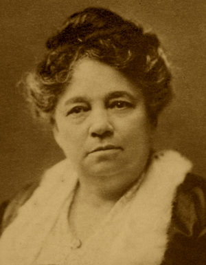 A middle-aged African-American woman, hair in an updo, wearing a dress or blouse with a wide square lacy collar.