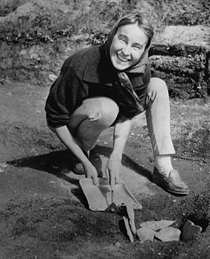 woman kneeling in the field with brush and dustpan