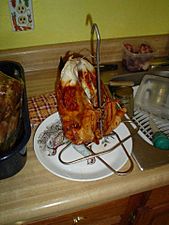 A whole turkey, browned on the outside, on a metal stand.