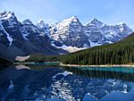 Lake, snow-covered mountains, and fir forest scenery