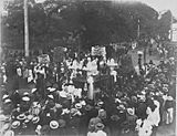 Crowds of people watching a catafalque pass by