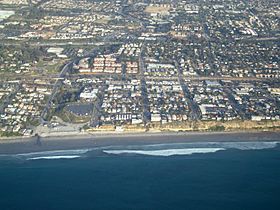 Aerial view of part of old town Encinitas showing Moonlight Beach on the left. Parallel with the shore is Historic Coast Highway 101; also parallel and further inland is Interstate 5.