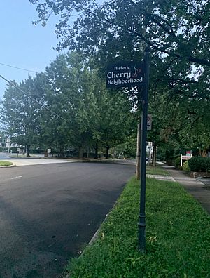 black street sign that says "Historic Cherry Neighborhood" with a picture of a cherry on the sign