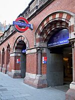 A red-bricked building with a dark blue sign reading "KING'S CROSS ST. PANCRAS" in white letters and several entranceways all under a grey sky