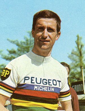 Tom Simpson wearing a white cycling jersey with horizontal rainbow stripes across the body