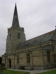 Part of a stone church seen from the south-east, with a protruding south aisle, and a tower surmounted by a spire