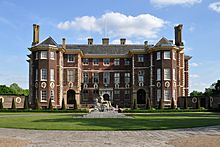 A view of Ham House from the front gates, showing the whole of the building with a statue of a reclining figure, known as Father Thames, in the foreground