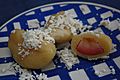 dumplings on a plate, one cut open to show fruit inside, all topped with cottage cheese