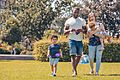 A mixed-race family walking in a park with European flags (P044728-798775)