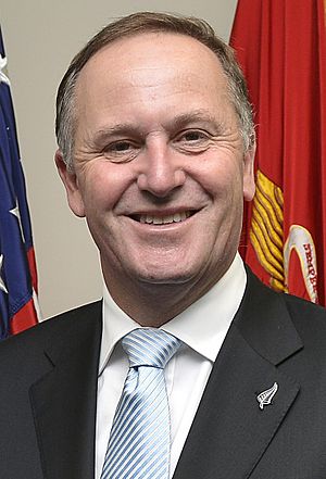 Head and shoulders of a smiling man in a dark suit and pale blue spotted tie