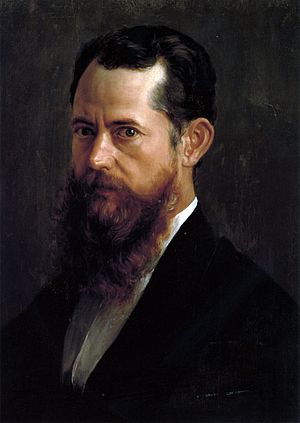 A head and shoulders portrait of a middle aged man, with a brown beard, facing to the left