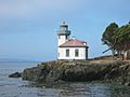 A small lighthouse on a rocky near a rocky coastline