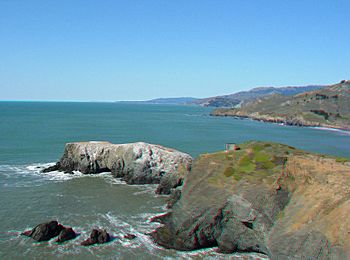 Clear blue skies above teal water crashing gently into rocky slopes rising out of the surf. The island majestic.