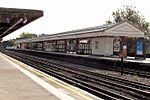 A grey railway platform with a railway track running down the middle and a rectangular, red sign reading "WHISTLE" in white letters