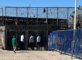 The gates of the buffer zone are topped with barbed wire that still carries some torn clothing (cropped).png