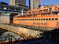 An orange Staten Island Ferry ship; the words "Staten Island" are seen on the side of the ship.