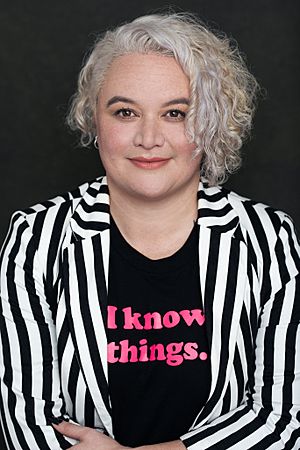 Whiti smiles at the camera, a women with curly hair and a striped jacket.