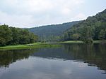 A reservoir surrounded by forested mountain ridges on either side and in the background.