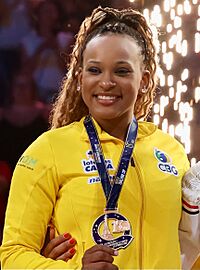 Andrade with a gold medal. She is a dark-skinned woman in her mid twenties with curly, brown hair wearing a yellow sports jersey.