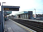 A railway platform with a railway track running through it from the left portion of the background to the right portion of the foreground